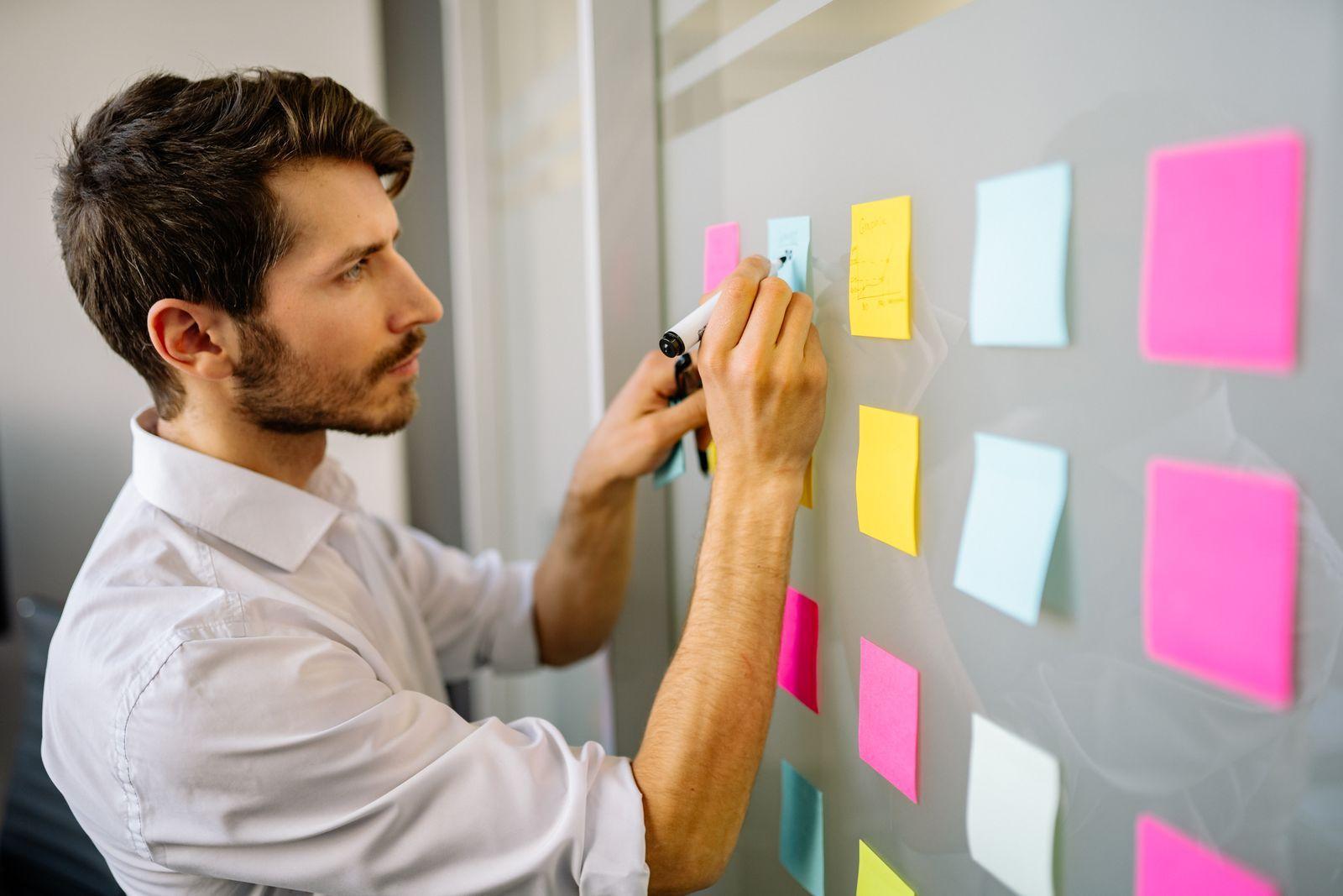 Pemilik bisnis memetakan proses kerja di papan tulis dengan sticky note
